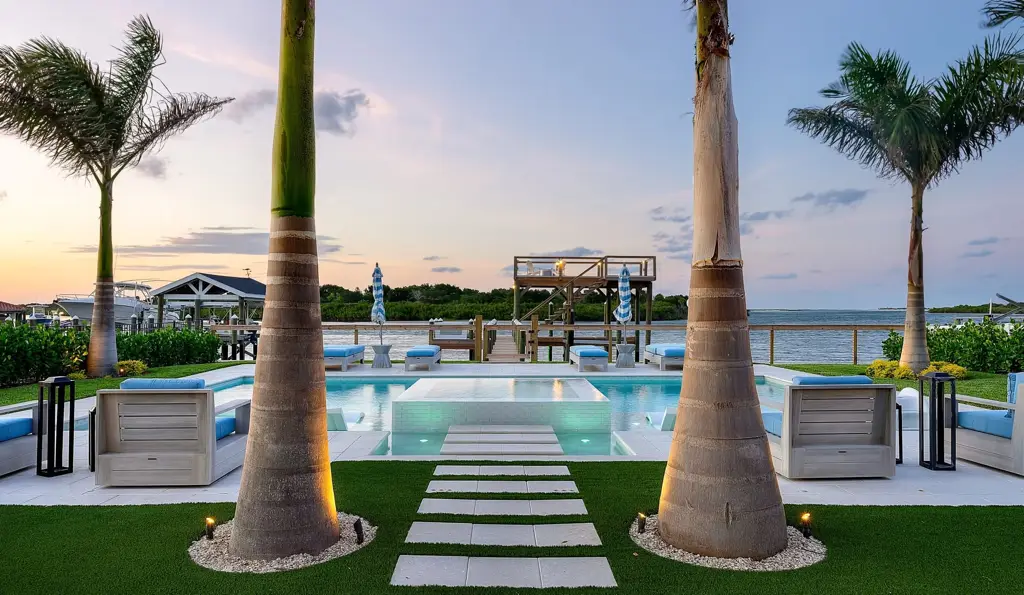 Waterfront pool with palm trees and a raised spa at dusk